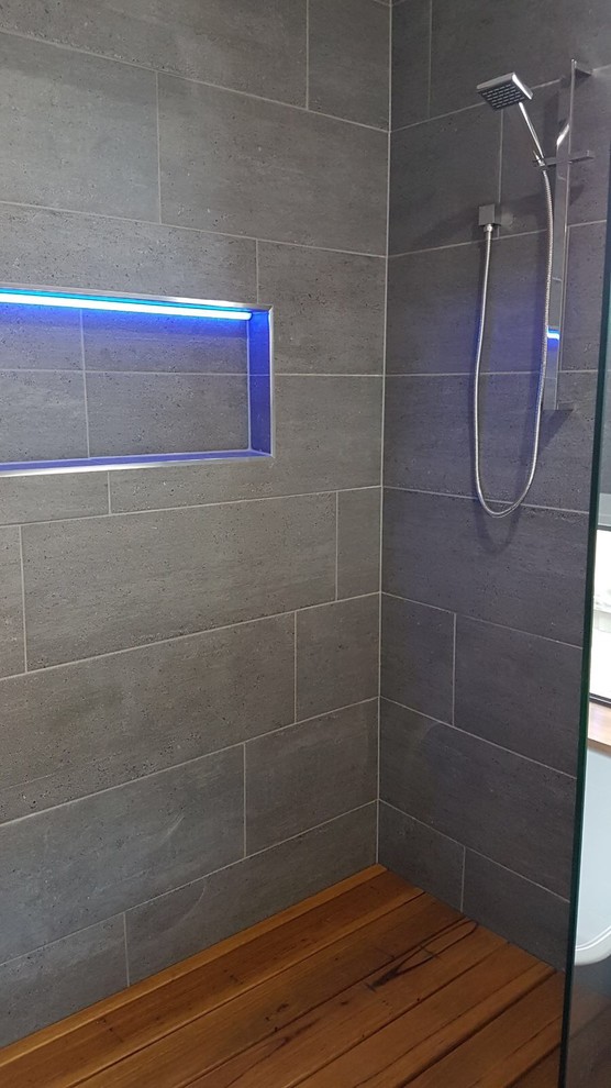 Photo of a medium sized contemporary ensuite bathroom in Geelong with a built-in shower, flat-panel cabinets, white cabinets, a freestanding bath, ceramic tiles, grey walls, terrazzo flooring, a vessel sink, wooden worktops, grey floors and a hinged door.