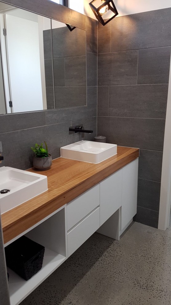 Example of a mid-sized trendy master ceramic tile terrazzo floor and gray floor bathroom design in Geelong with flat-panel cabinets, white cabinets, gray walls, a vessel sink, wood countertops and a hinged shower door