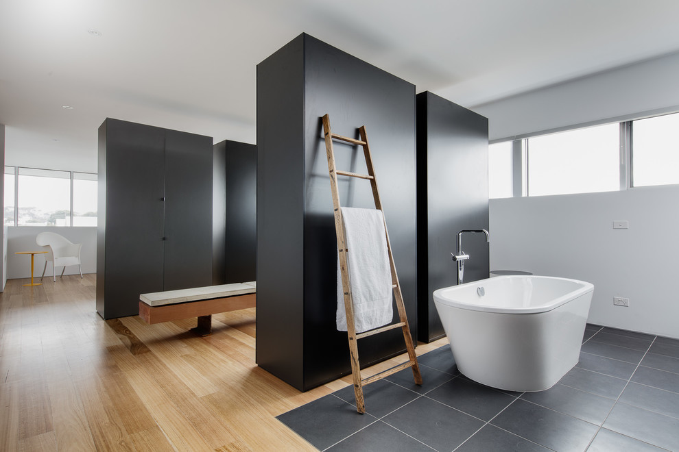 Источник вдохновения для домашнего уюта: огромная главная ванная комната в стиле модернизм с плоскими фасадами, черными фасадами, отдельно стоящей ванной, белыми стенами и паркетным полом среднего тона