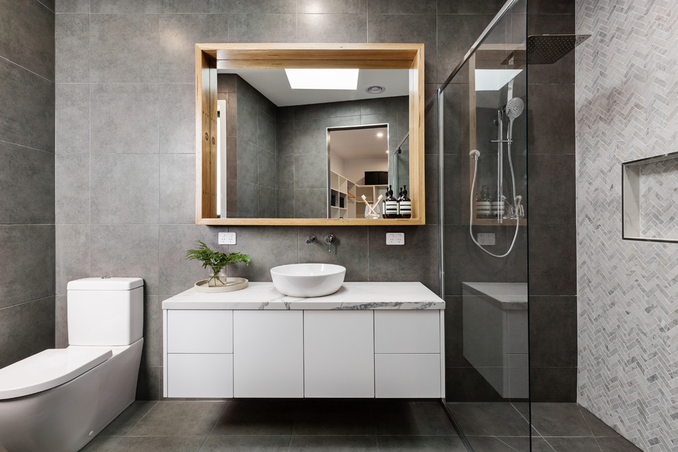 Inspiration for a mid-sized contemporary master gray tile and mosaic tile ceramic tile and gray floor walk-in shower remodel in Los Angeles with white cabinets, gray walls, a vessel sink, marble countertops, a hinged shower door, flat-panel cabinets and white countertops