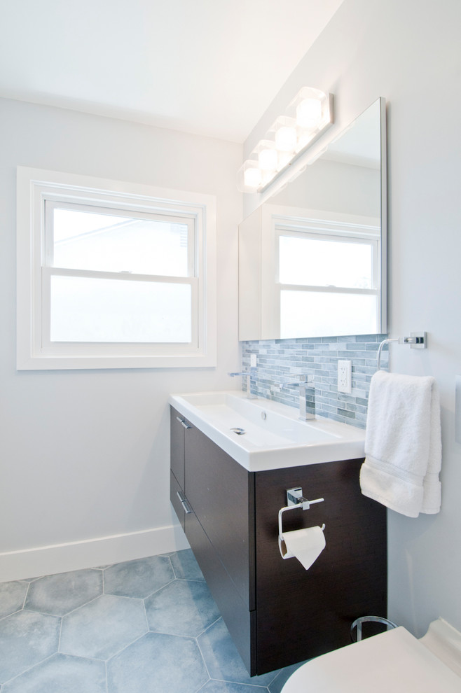 This is an example of a medium sized contemporary ensuite bathroom in Los Angeles with flat-panel cabinets, dark wood cabinets, an alcove shower, a one-piece toilet, blue tiles, glass tiles, white walls, porcelain flooring, an integrated sink, quartz worktops, blue floors, a hinged door and white worktops.