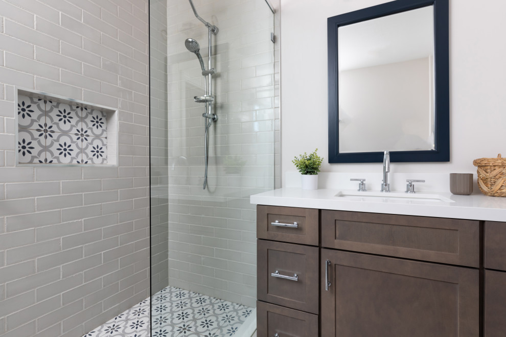 Foto på ett vintage vit badrum med dusch, med skåp i shakerstil, skåp i mellenmörkt trä, en dusch i en alkov, grå kakel, tunnelbanekakel, vita väggar, ett undermonterad handfat, flerfärgat golv och dusch med gångjärnsdörr