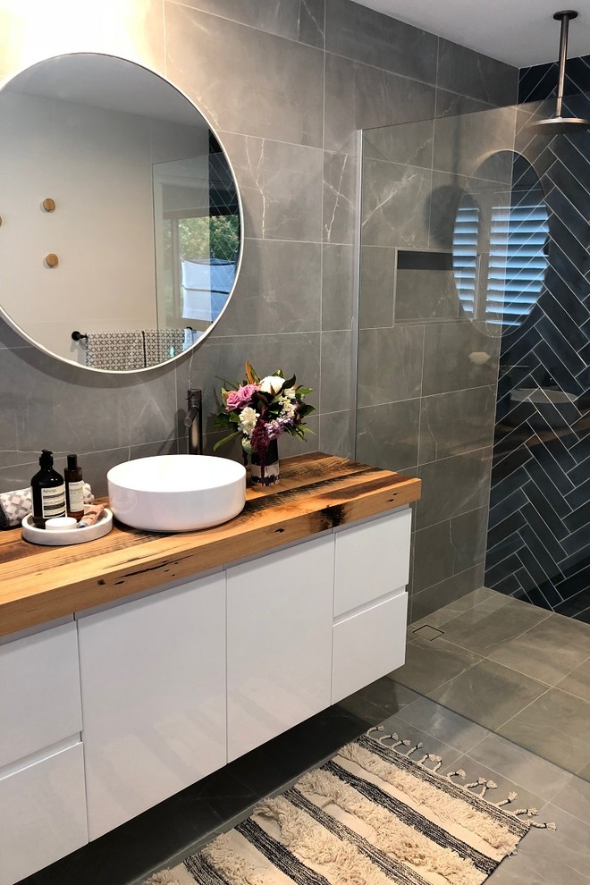 Diseño de cuarto de baño moderno de tamaño medio con baldosas y/o azulejos grises y encimera de madera
