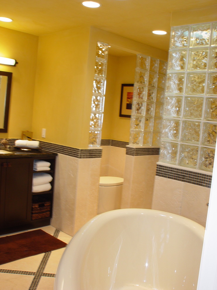 На фото: большая главная ванная комната в стиле фьюжн с фасадами в стиле шейкер, темными деревянными фасадами, черной плиткой, синей плиткой, стеклянной плиткой, столешницей из гранита, японской ванной, душем в нише, унитазом-моноблоком, желтыми стенами, полом из керамической плитки и врезной раковиной