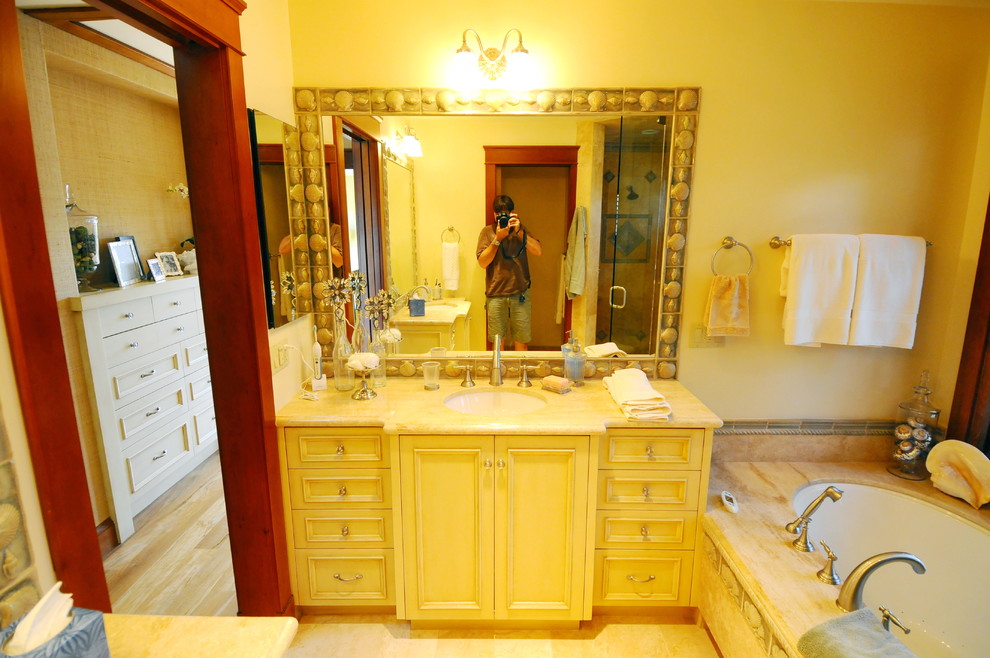 Idéer för att renovera ett mellanstort tropiskt en-suite badrum, med luckor med infälld panel, beige skåp, ett undermonterat badkar, en hörndusch, en toalettstol med separat cisternkåpa, gul kakel, travertinkakel, beige väggar, ljust trägolv, ett undermonterad handfat, bänkskiva i kalksten, brunt golv och dusch med gångjärnsdörr
