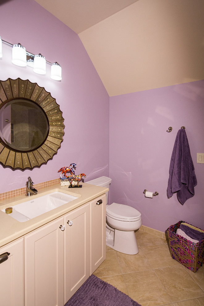 Cette photo montre une salle de bain chic de taille moyenne avec un placard à porte shaker, des portes de placard blanches, WC séparés, un carrelage beige, un mur violet, un sol en calcaire, un lavabo encastré et un plan de toilette en surface solide.