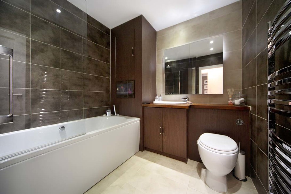 Foto di una stanza da bagno contemporanea di medie dimensioni con vasca da incasso, vasca/doccia, WC sospeso, piastrelle marroni, pareti marroni, lavabo da incasso e pavimento bianco