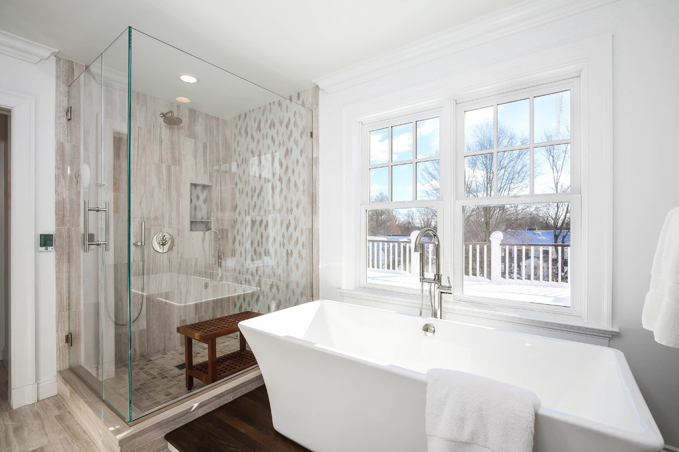 Идея дизайна: большая главная ванная комната в стиле неоклассика (современная классика) с плоскими фасадами, белыми фасадами, отдельно стоящей ванной, двойным душем, бежевой плиткой, каменной плиткой, белыми стенами, полом из известняка, врезной раковиной и стеклянной столешницей