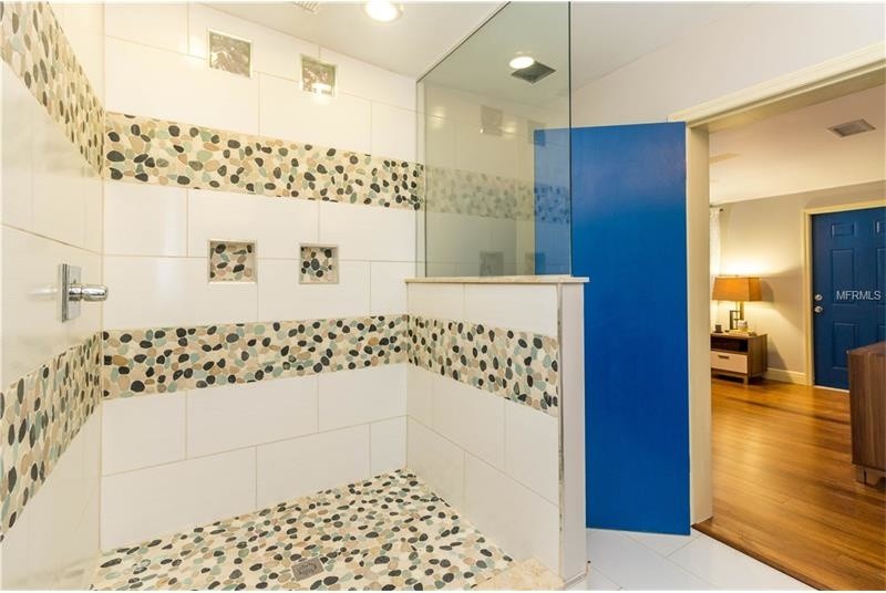 Idée de décoration pour une salle de bain design de taille moyenne avec une douche d'angle, un carrelage multicolore, une plaque de galets, un sol en carrelage de porcelaine, un sol blanc et aucune cabine.