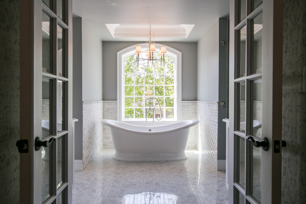 Esempio di un'ampia stanza da bagno padronale classica con ante di vetro, ante bianche, vasca freestanding, doccia doppia, WC monopezzo, piastrelle bianche, pareti grigie, pavimento in marmo, lavabo sottopiano e top in quarzite