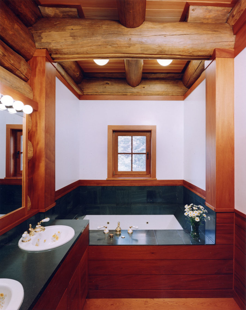 Cette photo montre une salle de bain principale montagne en bois foncé de taille moyenne avec un placard à porte plane, une baignoire encastrée, des carreaux de porcelaine, un mur blanc, parquet clair, un lavabo posé et un plan de toilette en surface solide.