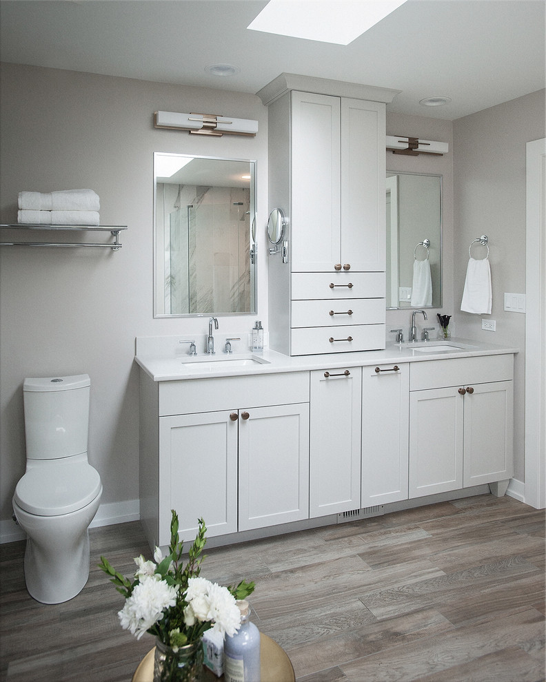 Cette photo montre une salle de bain principale chic de taille moyenne avec un placard à porte shaker, des portes de placard grises, une baignoire indépendante, une douche ouverte, WC séparés, un carrelage gris, des carreaux de porcelaine, un mur gris, un sol en carrelage de porcelaine, un lavabo encastré, un plan de toilette en quartz modifié, un sol multicolore, une cabine de douche à porte battante et un plan de toilette blanc.