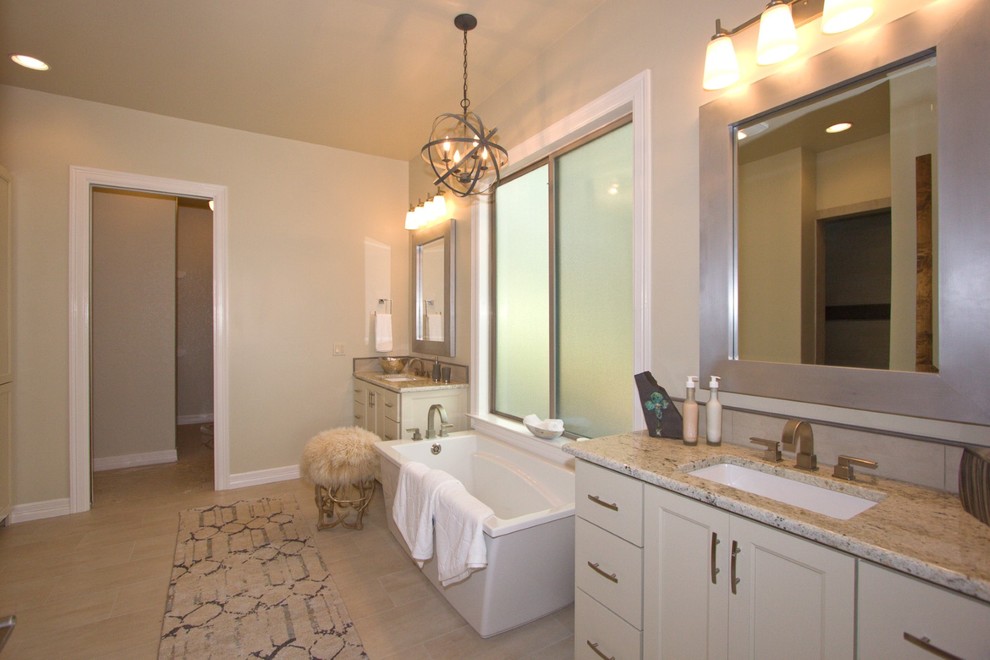 Photo of a large traditional ensuite bathroom in Austin with recessed-panel cabinets, white cabinets, a freestanding bath, beige walls, porcelain flooring, a submerged sink and granite worktops.