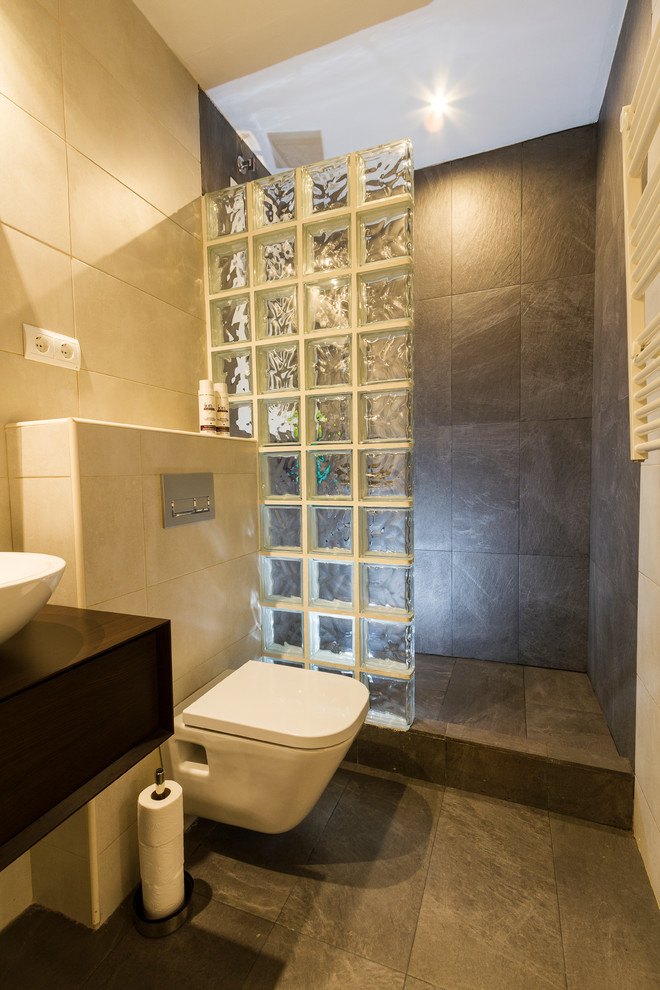 Ejemplo de cuarto de baño actual pequeño con ducha esquinera, sanitario de pared, paredes beige, suelo de baldosas de cerámica, aseo y ducha y lavabo sobreencimera