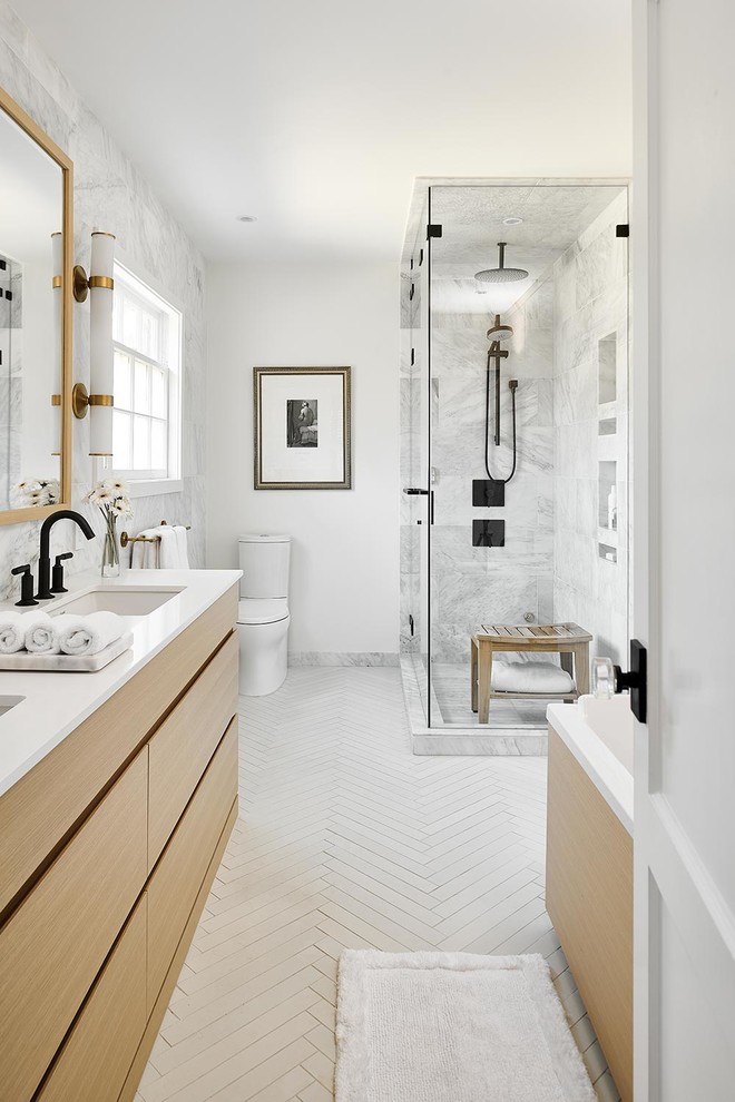 Example of a mid-sized trendy master beige tile and marble tile porcelain tile and beige floor bathroom design in Vancouver with flat-panel cabinets, light wood cabinets, a one-piece toilet, white walls, an undermount sink, quartz countertops, a hinged shower door and white countertops