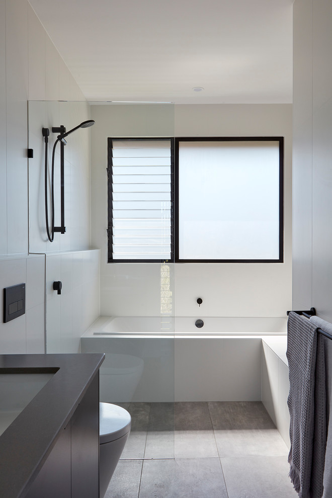 Inredning av ett modernt mellanstort grå grått en-suite badrum, med svarta skåp, en öppen dusch, en vägghängd toalettstol, vit kakel, vita väggar, klinkergolv i porslin, ett undermonterad handfat, bänkskiva i betong, grått golv och med dusch som är öppen