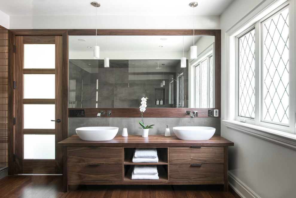На фото: ванная комната в современном стиле с настольной раковиной, темными деревянными фасадами, темным паркетным полом и окном