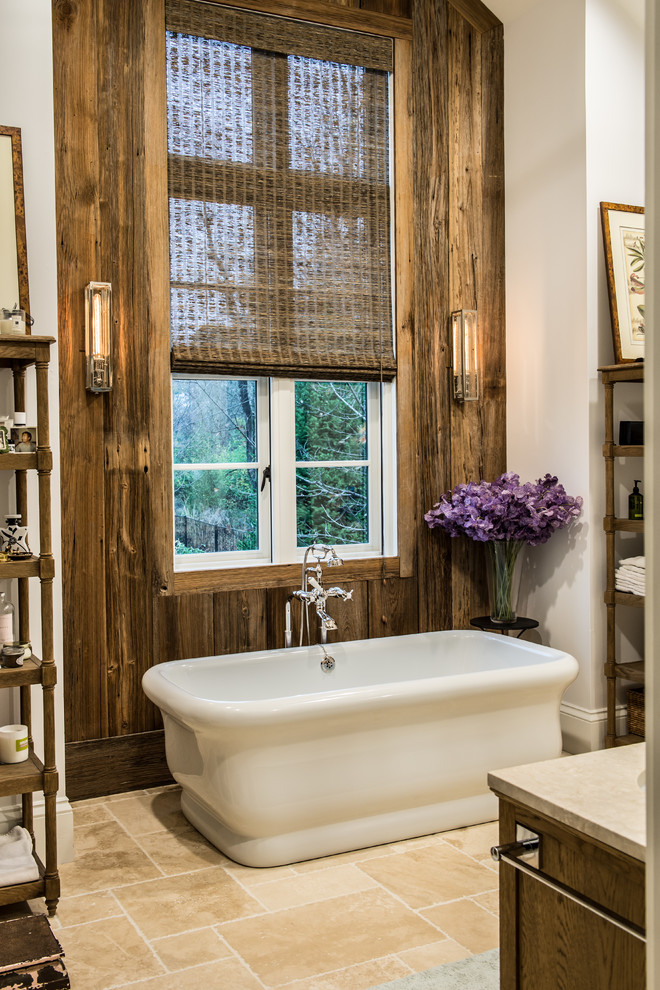 This is an example of a small rustic ensuite bathroom in St Louis with a freestanding bath, ceramic flooring, recessed-panel cabinets, light wood cabinets, a corner shower, beige tiles, beige walls and solid surface worktops.