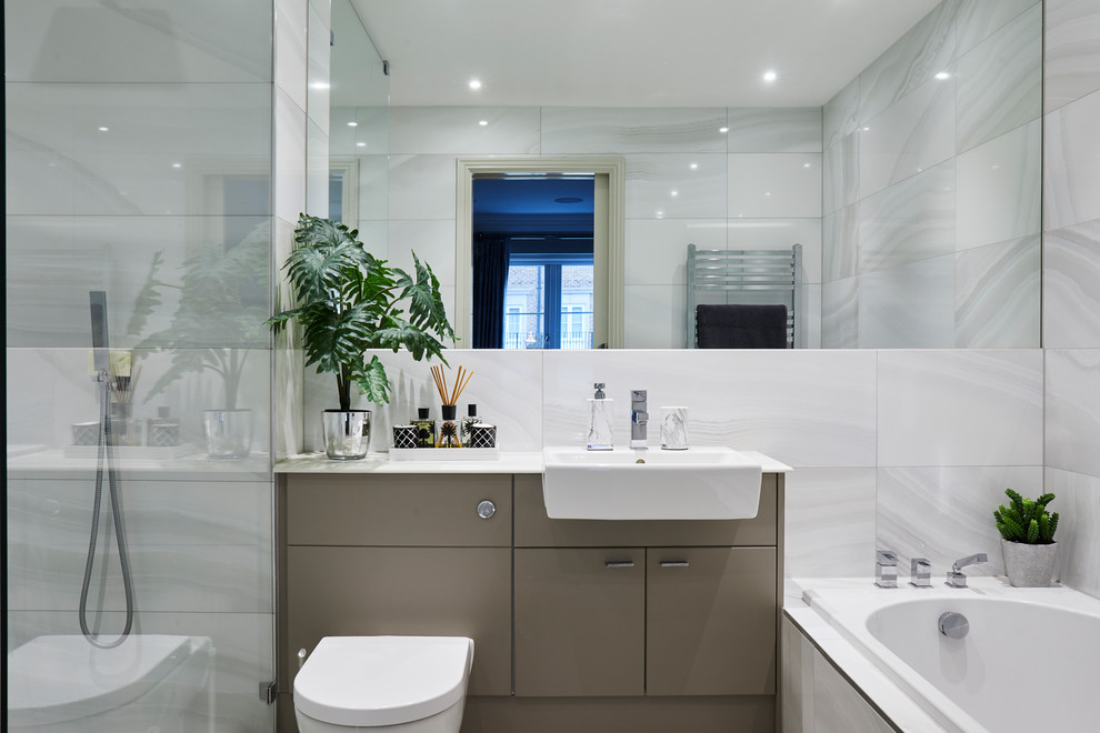 Modelo de cuarto de baño actual con puertas de armario grises, sanitario de una pieza, baldosas y/o azulejos grises, paredes grises, suelo de madera en tonos medios, lavabo encastrado, encimera de granito y encimeras grises