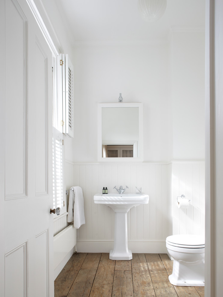 Idéer för ett klassiskt badrum, med ett piedestal handfat, vita väggar, mellanmörkt trägolv och brunt golv