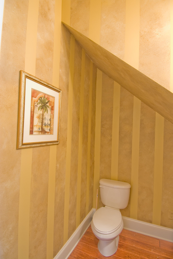 Imagen de aseo tradicional de tamaño medio con sanitario de dos piezas, paredes amarillas, suelo vinílico y lavabo con pedestal