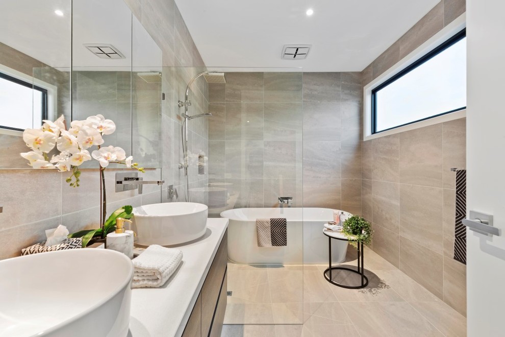 Modernes Badezimmer mit flächenbündigen Schrankfronten, dunklen Holzschränken, freistehender Badewanne, Nasszelle, beigen Fliesen, Aufsatzwaschbecken, beigem Boden, offener Dusche und weißer Waschtischplatte in Melbourne