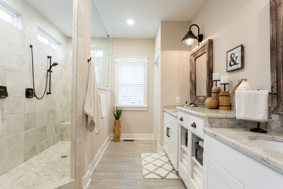 Modelo de cuarto de baño costero con armarios estilo shaker, puertas de armario blancas, baldosas y/o azulejos grises, paredes beige, lavabo bajoencimera y encimera de granito