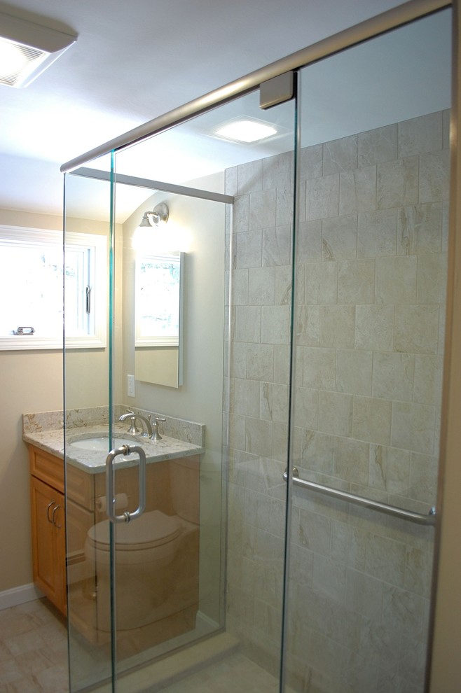Design ideas for a medium sized classic shower room bathroom in Boston with raised-panel cabinets, light wood cabinets, an alcove shower, a two-piece toilet, beige tiles, porcelain tiles, beige walls, porcelain flooring, a built-in sink, engineered stone worktops, beige floors and a hinged door.