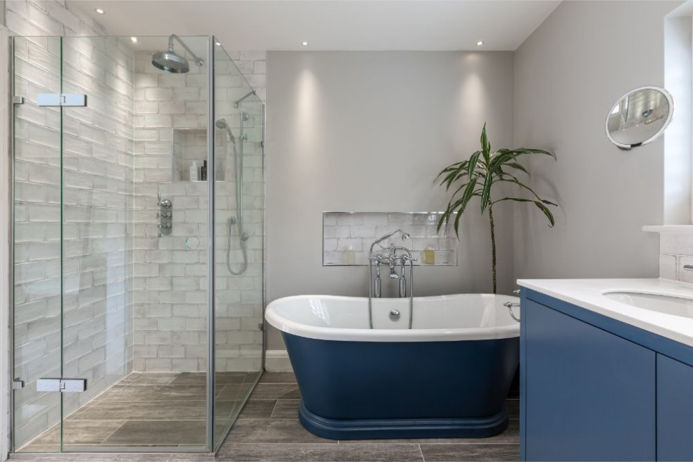 Свежая идея для дизайна: ванная комната в современном стиле с плоскими фасадами, синими фасадами, отдельно стоящей ванной, открытым душем, бежевой плиткой, зеркальной плиткой, бежевыми стенами, полом из керамогранита, столешницей из искусственного камня, серым полом, душем с распашными дверями, белой столешницей и врезной раковиной - отличное фото интерьера