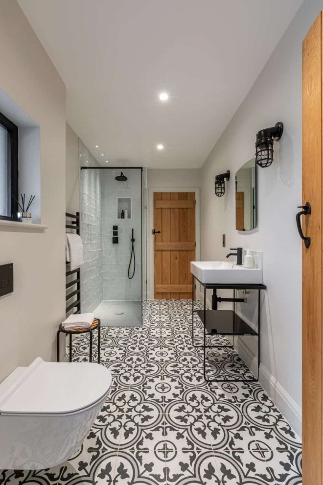 Example of a large trendy master multicolored floor and single-sink bathroom design in Berkshire with a wall-mount toilet, beige walls, a console sink and a niche