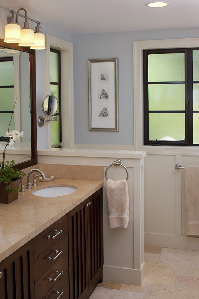 На фото: ванная комната в классическом стиле с врезной раковиной, темными деревянными фасадами и бежевой плиткой с