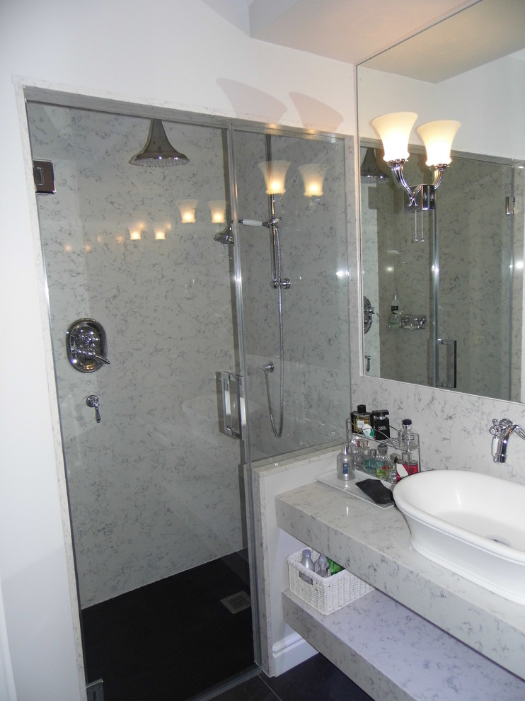 Foto på ett stort vintage en-suite badrum, med ett fristående handfat, öppna hyllor, bänkskiva i akrylsten, ett fristående badkar, en dusch i en alkov, en vägghängd toalettstol, svart kakel, porslinskakel, grå väggar och klinkergolv i porslin