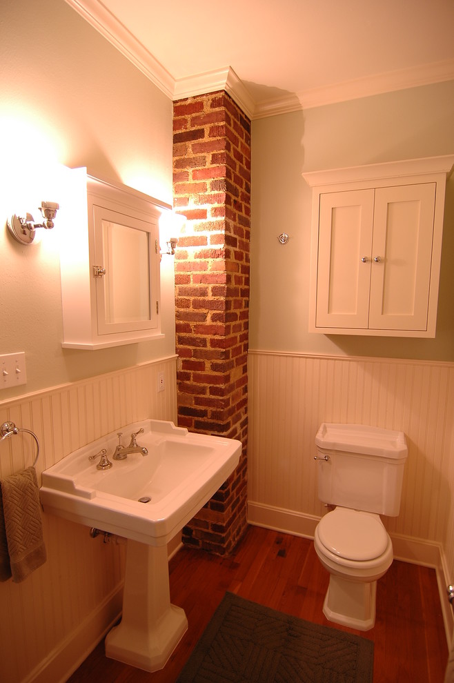 Foto de cuarto de baño tradicional pequeño con lavabo con pedestal, armarios estilo shaker, puertas de armario blancas, sanitario de dos piezas, paredes verdes y suelo de madera en tonos medios