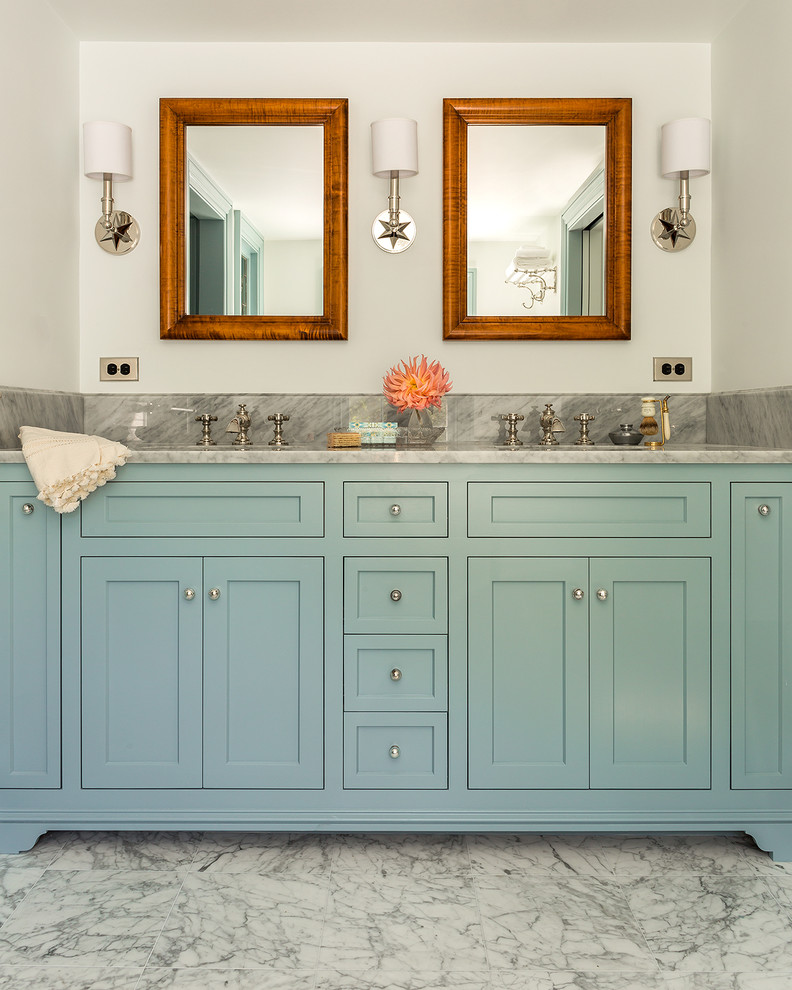 Diseño de cuarto de baño principal tradicional con lavabo bajoencimera, armarios estilo shaker, puertas de armario azules, encimera de mármol, paredes blancas, suelo de mármol y encimeras grises
