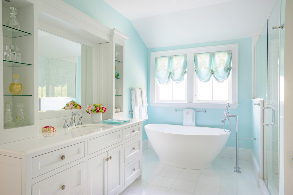 Ejemplo de cuarto de baño principal tradicional grande con armarios estilo shaker, puertas de armario blancas, bañera exenta, paredes azules, lavabo bajoencimera, suelo blanco y ventanas
