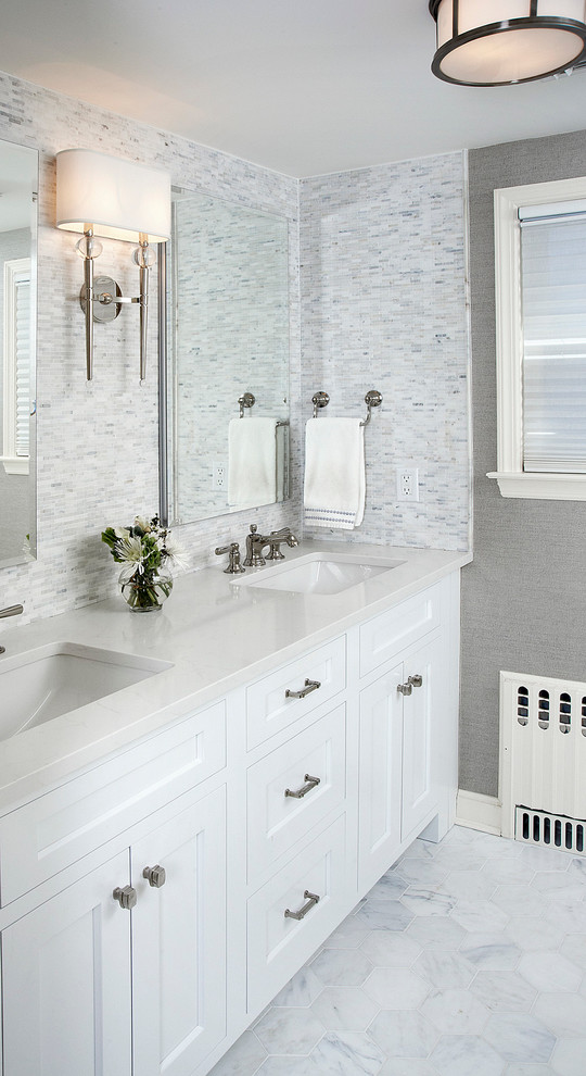 Modelo de cuarto de baño clásico con lavabo bajoencimera, armarios estilo shaker, puertas de armario blancas, baldosas y/o azulejos blancos y paredes grises