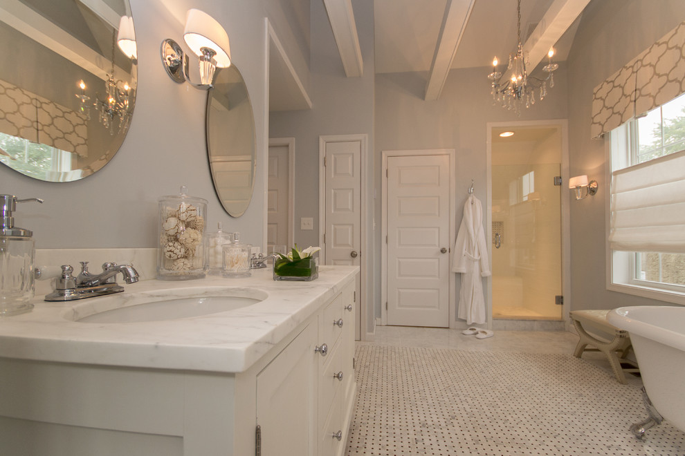 Cette image montre une grande salle de bain principale traditionnelle avec un placard en trompe-l'oeil, des portes de placard blanches, une baignoire sur pieds, WC à poser, un carrelage noir et blanc, mosaïque, un mur gris, un sol en marbre, un lavabo encastré et un plan de toilette en marbre.