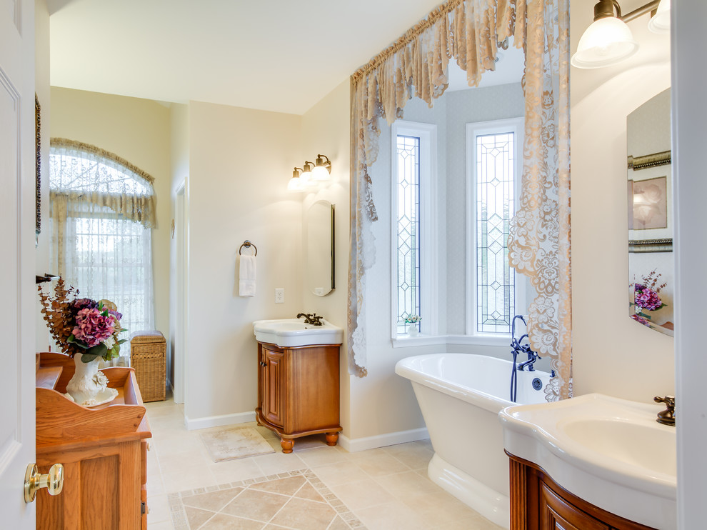 Inspiration för klassiska badrum, med ett konsol handfat, skåp i mellenmörkt trä, ett fristående badkar, beige väggar och luckor med upphöjd panel