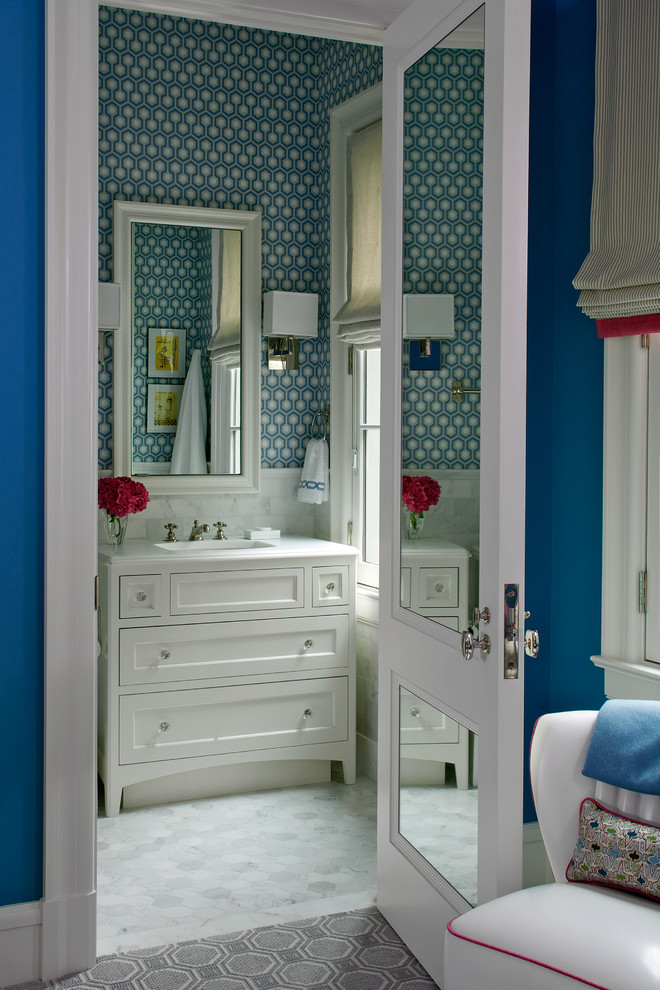 Cette image montre une salle de bain traditionnelle avec un lavabo intégré, un placard à porte shaker, des portes de placard blanches, un carrelage blanc et un mur multicolore.