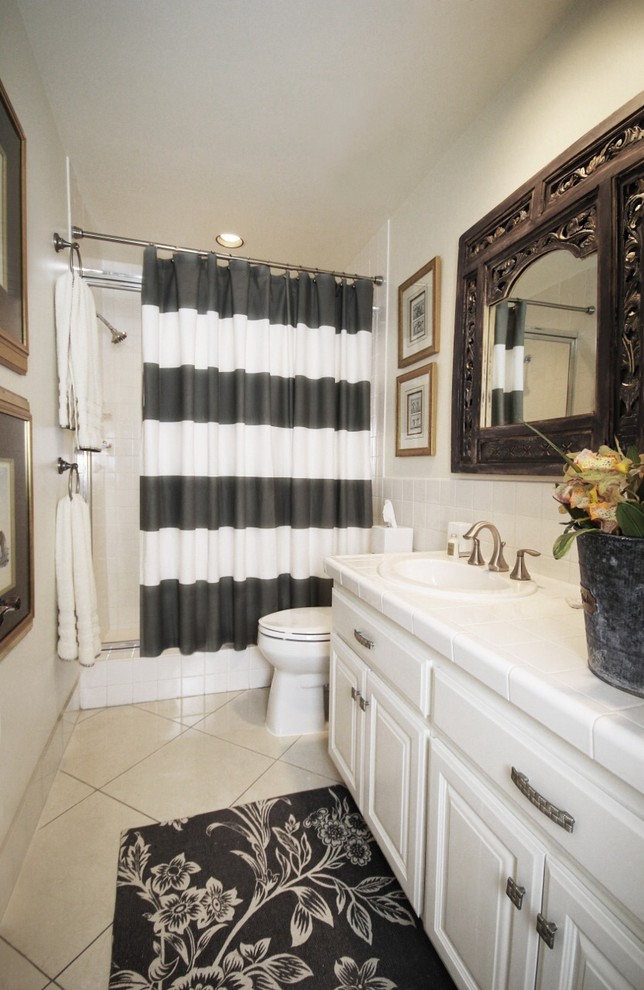 Inspiration for a timeless white tile single-sink bathroom remodel with raised-panel cabinets, white cabinets, a one-piece toilet, beige walls, a drop-in sink, tile countertops, white countertops and a built-in vanity