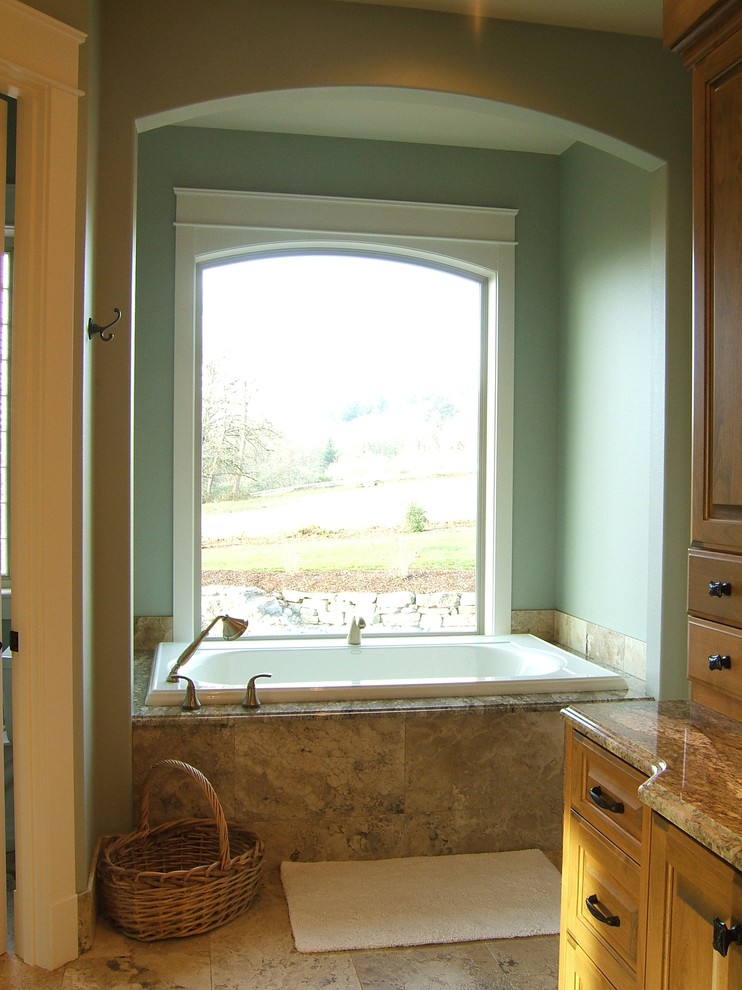 Idée de décoration pour une salle de bain tradition en bois brun avec un placard avec porte à panneau surélevé, une baignoire posée et un carrelage beige.