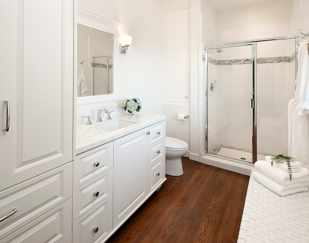 Example of a mid-sized classic 3/4 white tile and ceramic tile dark wood floor alcove shower design in Santa Barbara with an undermount sink, raised-panel cabinets, white cabinets, marble countertops and white walls