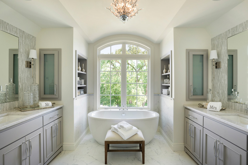 Пример оригинального дизайна: большая главная ванная комната в классическом стиле с фасадами с декоративным кантом, серыми фасадами, отдельно стоящей ванной, серой плиткой, белыми стенами, мраморным полом, врезной раковиной, столешницей из кварцита и белым полом