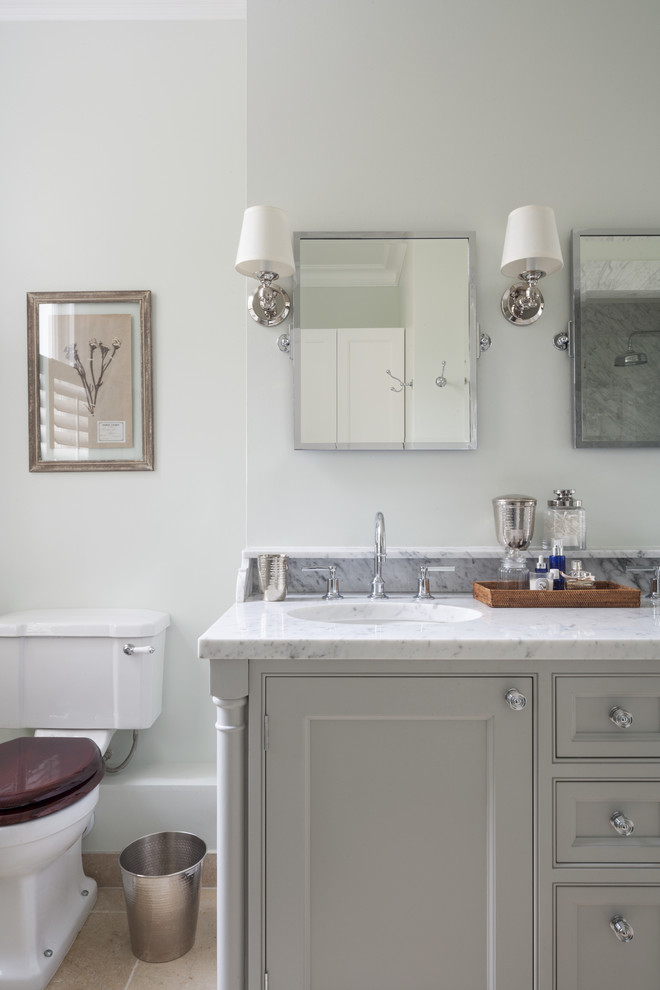 Photo of a medium sized traditional ensuite bathroom in London with a submerged sink, recessed-panel cabinets, marble worktops, a built-in bath, a built-in shower, a one-piece toilet, limestone flooring, grey cabinets and grey walls.