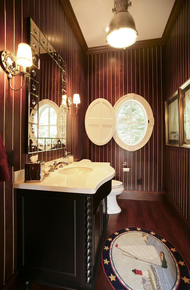 Cette photo montre une petite salle de bain chic avec un placard avec porte à panneau surélevé, des portes de placard noires, WC séparés, parquet foncé, un lavabo encastré, un plan de toilette en marbre et un mur marron.