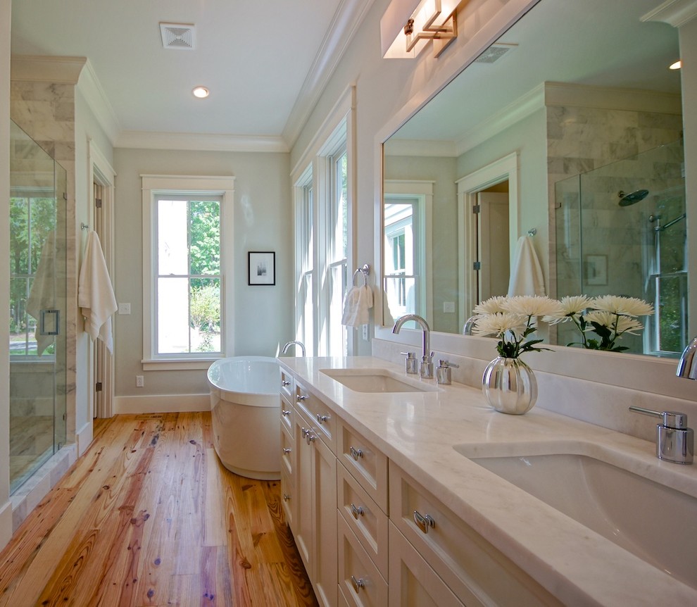 Klassisk inredning av ett badrum, med ett fristående badkar, ett undermonterad handfat och ljust trägolv