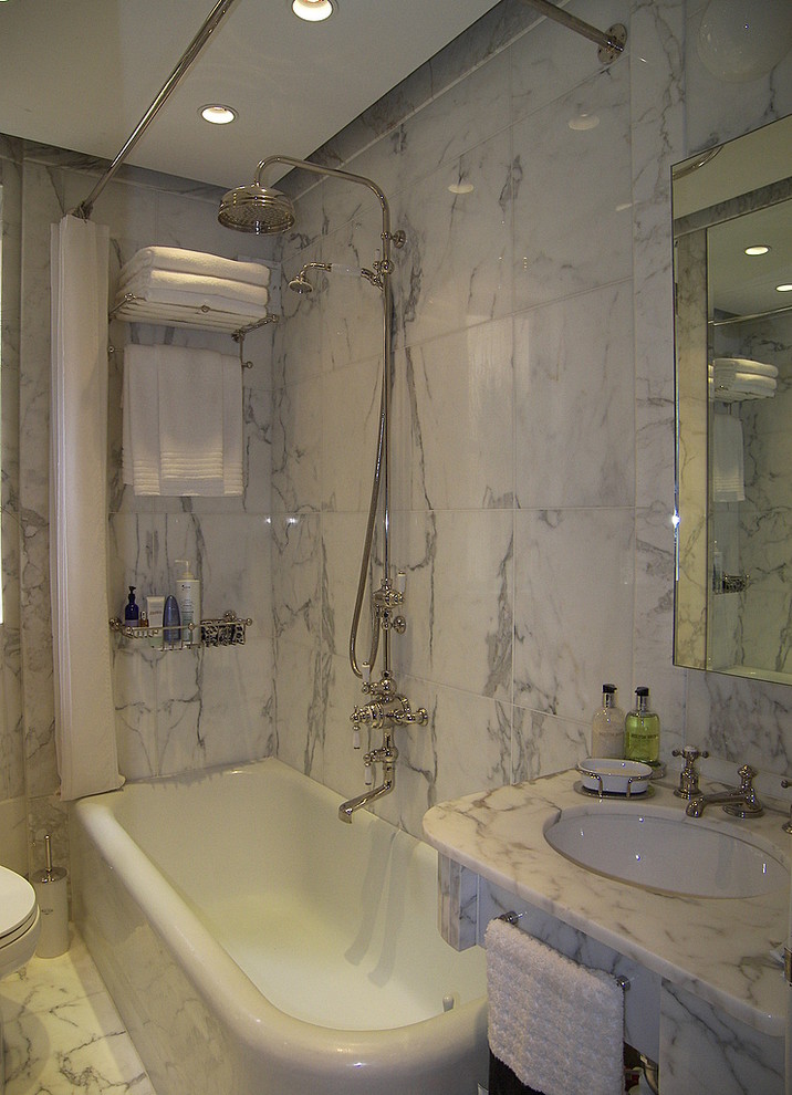 Ispirazione per una piccola stanza da bagno chic con lavabo sottopiano, top in marmo, vasca ad angolo, vasca/doccia, WC monopezzo, piastrelle bianche e piastrelle in pietra
