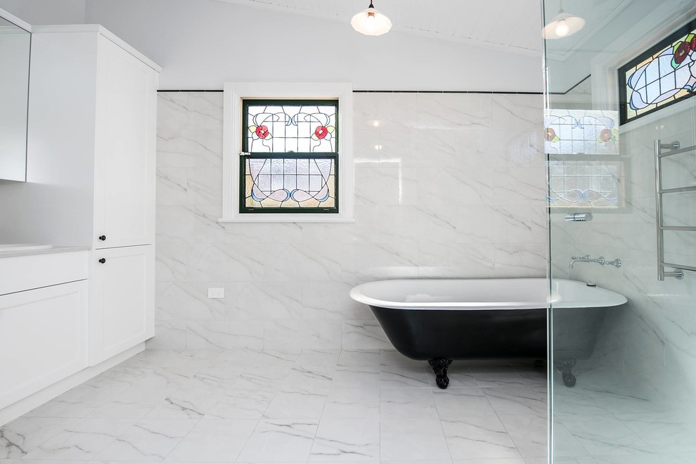 Источник вдохновения для домашнего уюта: главная ванная комната среднего размера в классическом стиле с отдельно стоящей ванной, унитазом-моноблоком, белой плиткой, мраморной плиткой, белыми стенами, мраморным полом, белым полом, душем с распашными дверями, фасадами с утопленной филенкой, белыми фасадами, душем в нише, накладной раковиной, мраморной столешницей, белой столешницей, тумбой под две раковины и встроенной тумбой
