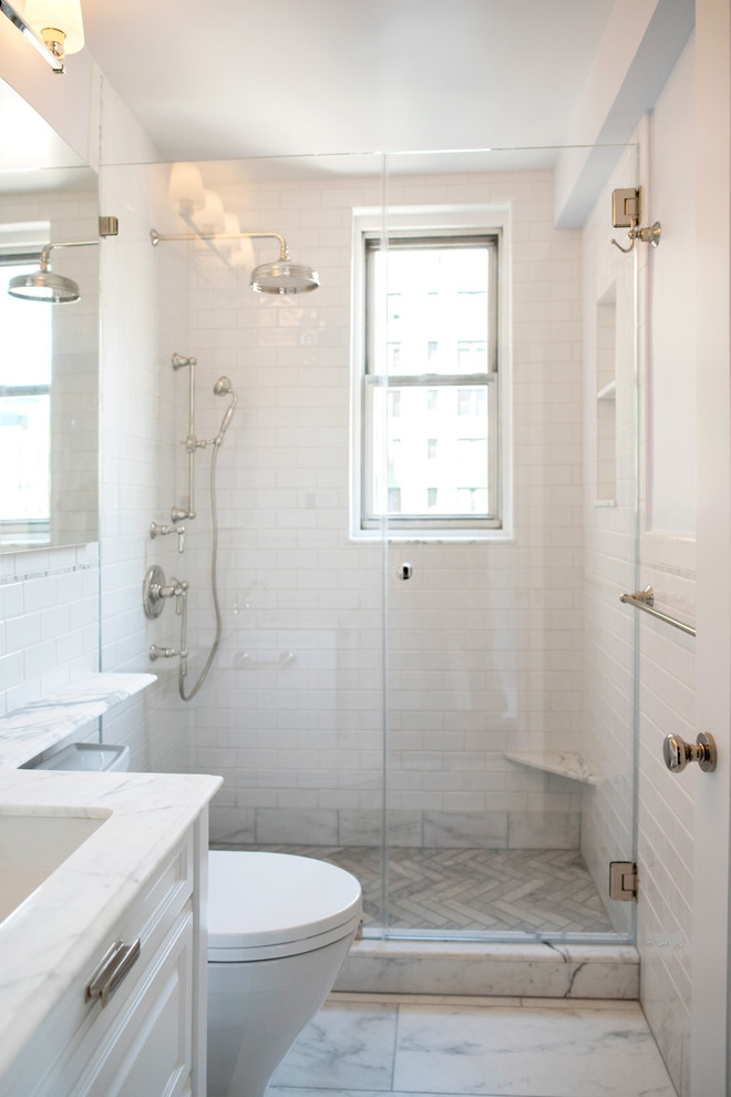 Klassisk inredning av ett litet en-suite badrum, med luckor med upphöjd panel, vita skåp, en dusch i en alkov, en toalettstol med hel cisternkåpa, vit kakel, stenkakel, vita väggar, marmorgolv, ett nedsänkt handfat och bänkskiva i kvartsit