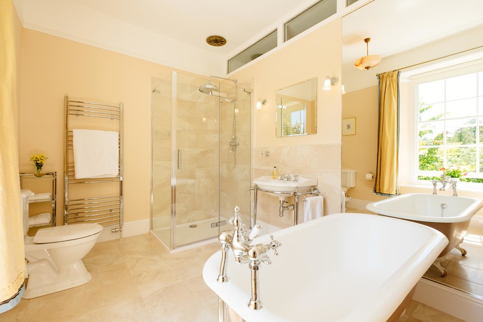 Klassisches Badezimmer mit Waschtischkonsole, Löwenfuß-Badewanne, Eckdusche, beiger Wandfarbe und Toilette mit Aufsatzspülkasten in Cornwall
